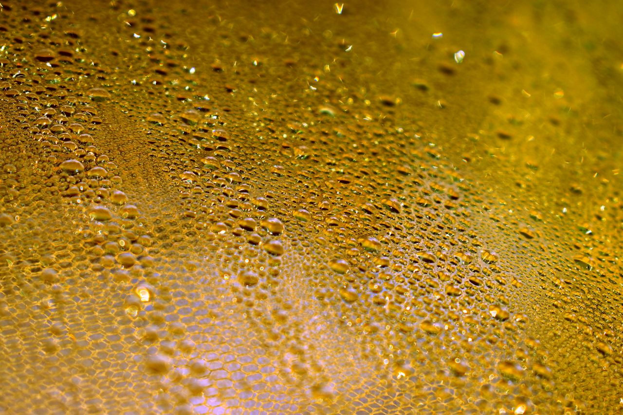 Macro of golden liquid and glass in fine light